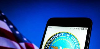 Smartphone showing Department of Defense logo, American flag background.