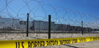 Border patrol tape and barbed wire fence.
