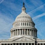 U.S. Capitol building dome against blue sky.