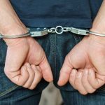 Person in handcuffs behind their back.