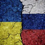 Cracked Ukrainian and Russian flags painted on concrete.