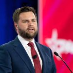 Man in suit speaking at podium.
