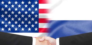 Hands shaking in front of USA and Russia flags.
