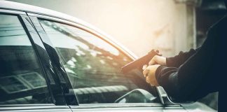 Person pointing gun at a car window.