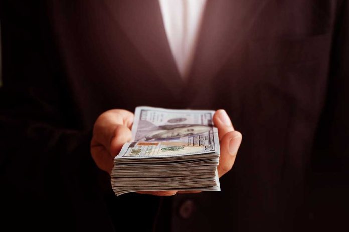 71912373 featured image Hand holding a stack of hundred-dollar bills.