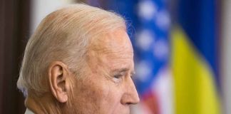 Side profile of a man with blurred flags behind