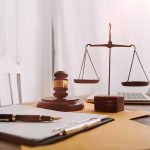 Gavel, scales, pen, and papers on a desk.