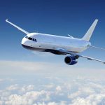 Airplane flying above fluffy white clouds sky
