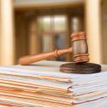Gavel resting on stack of paperwork in courtroom.
