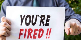 Person holding YOU'RE FIRED sign.