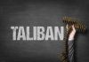 Word Taliban with hand holding ammunition belt
