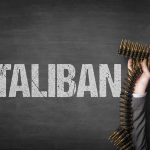 Word Taliban with hand holding ammunition belt