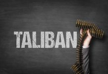 Word Taliban with hand holding ammunition belt