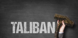 Word Taliban with hand holding ammunition belt