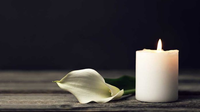 1658063071 featured image White candle and calla lily on wooden surface.