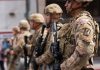 Soldiers in camouflage standing in a line with rifles