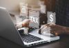 Person typing on laptop with tax related icons displayed