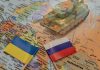 Toy tank on map with Ukraine and Russia flags