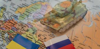 Toy tank on map with Ukraine and Russia flags