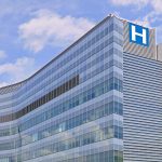 Modern glass hospital building under blue sky