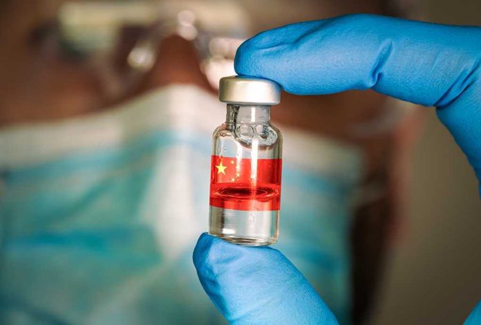 Gloved hand holding vial with red liquid and flag