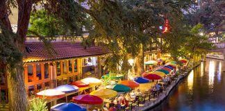 Outdoor riverside restaurant with colorful umbrellas and evening lights