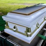 White casket on a lowering device at gravesite