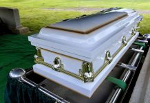 White casket on a lowering device at gravesite