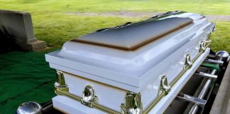 White casket on a lowering device at gravesite