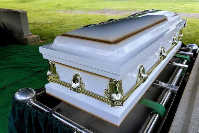 2412113605 featured image White casket on a lowering device at gravesite