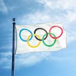 Olympic flag waving against a clear blue sky