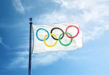 Olympic flag waving against a clear blue sky