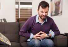 Man sitting on couch holding stomach in pain