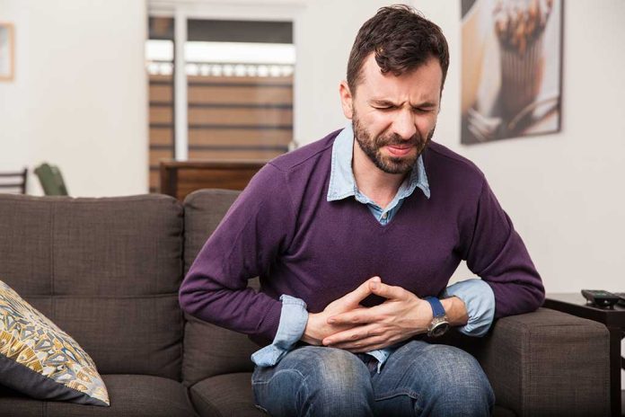 Man sitting on couch holding stomach in pain
