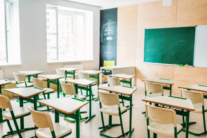 classroom_207646682 featured image Empty classroom with desks facing a chalkboard