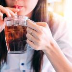 Person drinking soda from a glass mug