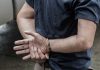Person in handcuffs with hands behind back.