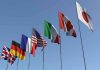 Flags of seven countries against clear blue sky