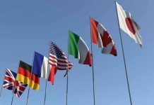 Flags of seven countries against clear blue sky
