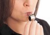 Person blowing a silver whistle close up