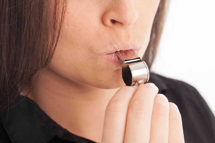 Person blowing a silver whistle close up