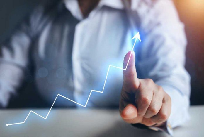 1936001935 Person pointing at an upward trend line graph