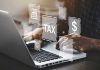 Person typing on laptop with tax-related icons displayed