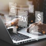 Person typing on laptop with tax-related icons displayed