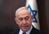 Man in suit with Israeli flag in background