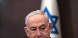 Man in suit with Israeli flag in background