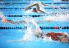 Swimmers competing in a pool creating splashes of water