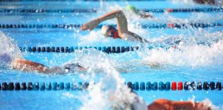 Swimmers competing in a pool creating splashes of water