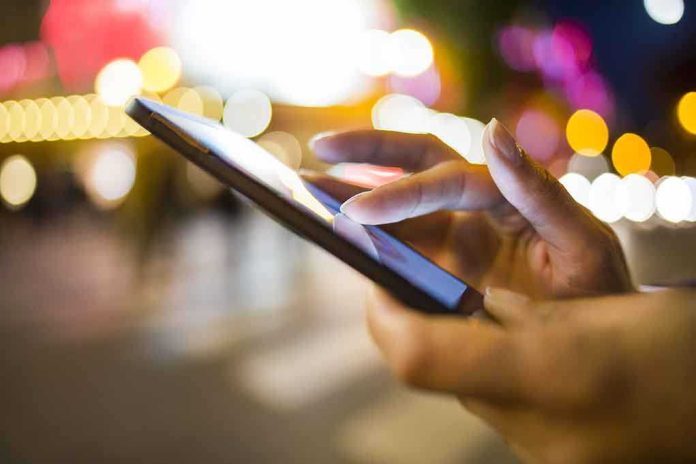 shutterstock_160559990.jpg A persons hand using a smartphone in a city at night with blurred lights in the background