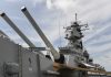 Close up of a battleship's naval guns and superstructure against a cloudy sky